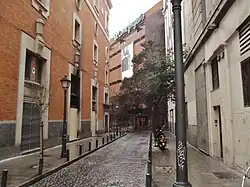 Al fondo, recodo de la calle con la entrada trasera de unos grandes almacenes.