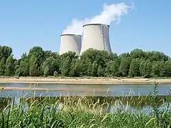 Nuclear power plant in Cattenom, France four large cooling towers expelling white water vapour against a blue sky