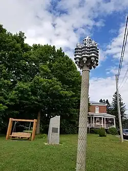Castillo de pájaro de la época del párroco Maxime Masson y piedra del Centenario, instalado en el frente parterre del presbiterio.