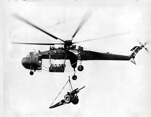 Un helicçoptero Sikorsky CH-54 Tarhe transportando un obús de 105 mm a una posición avanzada en Vietnam. El uso del CH-54 agilizaría el posicionamiento de la artillería en zonas inaccesibles por carretera, permitiendo levantar el obús remolcado de 155 mm sin dividirlo.