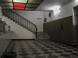 Interior del edificio, mostrando una barra de buffet, unos plafones con luces de color y una escalera que asciende