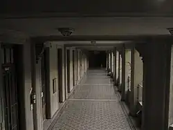 Galería techada con puertas en el lado izquierdo y aberturas a un patio (no visible) en el lado derecho.