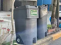 contenedor de basura color gris con 2 ruedas