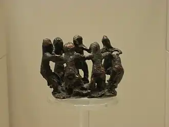 Grupo de siete mujeres desnudas bailando en círculo (¿ninfas?), ofrenda a Zeus, bronce (siglo&nbsp;VIII&nbsp;a.&nbsp;C.)