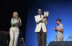 En la imagen se ve a Luz mostrando la placa con su distinción de Ciudadano Ilustre y a su derecha la intendenta Cosse aplaudiendo.