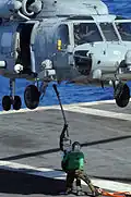 Marineros de la Armada de Estados Unidos enganchan un cable de carga a un helicóptero Sikorsky SH-60 Seahawk asignado al Escuadrón de Helicópteros Anti-Submarinos 4 durante una maniobra de reabastecimiento vertical en el Océano Pacífico el 16 de julio de 2010.