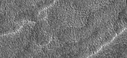 Primer plano del terreno festoneado, visto por HiRISE bajo el programa HiWish. La superficie se divide en polígonos; estas formas son comunes donde el suelo se congela y se descongela. Nota: esta es una ampliación de una imagen anterior.
