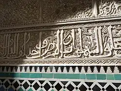 Inscripción con caligrafía arábica en letra cursiva, tallada en estuco en la Madrasa de al-Attarine en Fez (principios del siglo&nbsp;XIV)