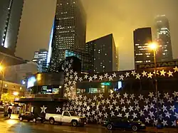 Night downtown, shot tilted to right; silver stars on black painted exterior of First Avenue, several tall black buildings with lights in rear, black cars and white truck parked in front