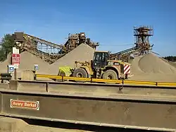 Excavadora delante de montones de grava