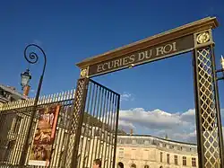 Detalle de la reja de acceso con el lema "Écuries du Roi" (Caballerizas del Rey).