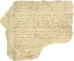 Una pequeña sección irregular de pergamino sobre la cual son visibles varias líneas de texto manuscrito. Varias firmas elaboradas enmarcan el texto, en la parte inferior.