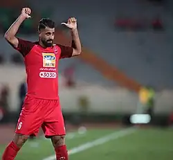 El futbolista iraní Hossein Kanaani celebra un gol señalando su nombre y dorsal en la espalda.