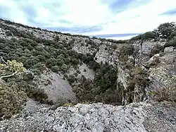 Hoya o dolina de la Redondilla, cercana a la aldea de Zenzano (La Rioja), en la que se aprecian las paredes de caliza del Cretácico inferior que han quedado expuestas por el colapso y formación de la dolina debido a la disolución kárstica de los depósitos subyacentes.