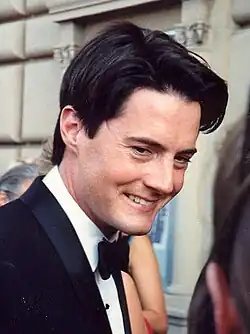 A man in his 30s, wearing a suit with a black bow tie.