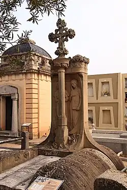 Conill-Aldrich (1906). Una estela con dos figuras -la Esperanza y la Fe- ante las cuales hay una columna que sostiene un capitel que representa la caridad.