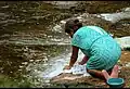 Mujer lavando en un río.