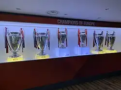 Four trophies inside a glass cabinet. The trophies have ribbons on them and there is memorabilia next to them