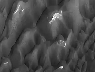 Cráter Lyot, en detalle se ven depósitos de leve tonalidad y pistas causadas por torbellinos de viento.