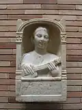 Estela conmemorativa de una mujer romana de 16 años, representada tocando un instrumento tipo pandura, fecha estimada del siglo II d.C. Desenterrada en 1956 en el sitio arqueológico Emerita Augusta en España. Conservada en el Museo Nacional de Arte Romano de Mérida, España[8]​