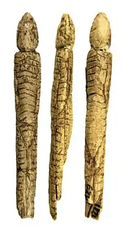 Figura alargada con capucha y decoración, y restos de pintura.[10]​