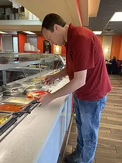 Un cliente toma comida de un buffet en un restaurante..