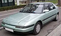 Un automóvil Mazda 323/protegé modelo 1994 en un aparcamiento público.