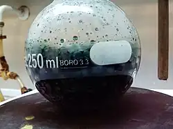 Mezcla crómica, ya reducida, en plena ebullición. El color verde se debe a los iones Cr(III) que se obtienen como producto.