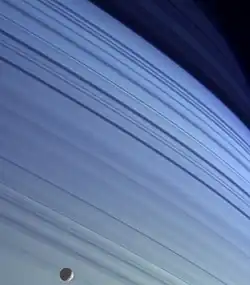 Silueta de Mimas, contrastando con las latitudes más septentrionales de Saturno.