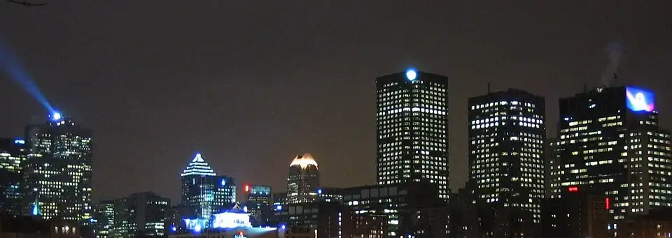 Vista nocturna desde la Place d'Armes; el faro que se ve a la izquierda está situado en la Place Ville-Marie.