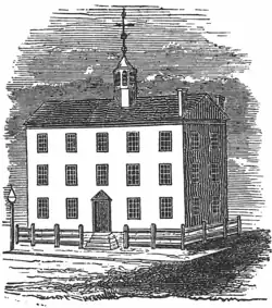 Black and white engraving shows a three-story building with a gabled roof and a belfry.