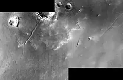 Cráter Paros con su manto de eyección sur y una grieta que cruza desde el borde sur hacia el exterior de la eyección, hacia una grieta más corta y tenue en la superficie más antigua.