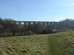 stone viaduct with múltiple arches, partly obscured by tress