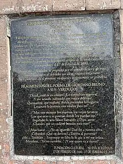 Fotografía tomada desde el este. Se aprecia la placa descriptiva que brinda información acerca del monumento a Giordano Bruno que se sostiene sobre un pedestal.