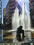 La Fuente de los Niños con los edificios de la plaza de fondo