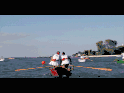 Mujeres que reman en barco rojo, en la laguna de Venecia. Día soleado. Mujeres vestidas con una camiseta blanca y una minifalda blanca.