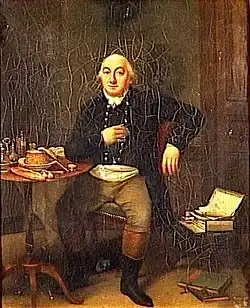 En un interior, hombre sentado a la mesa, pero mirando al espectador de frente, con chaqueta oscura, pantalón ocre y botas hasta la rodilla, negras por abajo y marrones por arriba. Sobre la mesa, un velador parece haber comida.