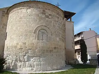 Ábside románico con zócalo de piedra de sillería, sin adornos, sin contrafuertes ni columnas.