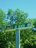Señal de Shades of Death road impresa en una viga de acero