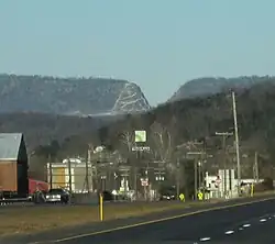 A small town is seen below a mountain ridge which contains a deep V-shaped cut.