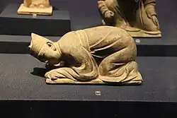 Estatuilla de un funcionario chino realizando el kowtow.