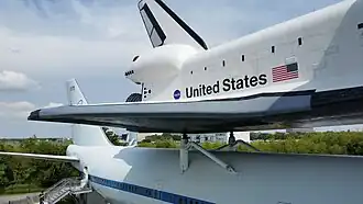 The Shuttle Independence sits atop the Shuttle Carrier Aircraft with the Johnson Space Center and Rocket Park in the background