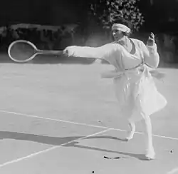 Lenglen hitting a forehand near the baseline in the doubles alley