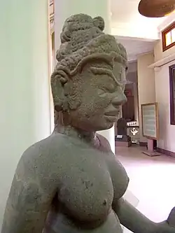 Estatua de Tara en arenisca del siglo&nbsp;IX, con una pequeña figura de Amitabha sentada en su cabello por encima de la frente.