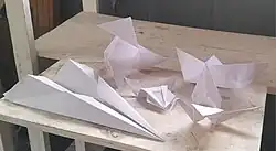 Figuras tradicionales de origami que representan a una pajarita, un barco, un avión, una rana y una grulla