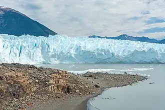 Turistas (centro) caminando junto al glaciar.