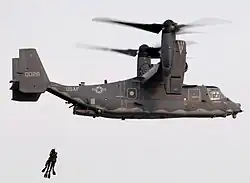 Dos buzos SEAL siendo izados por un convertiplano CV-22 Osprey.