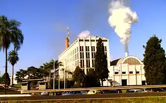 Photo of shorter building with smoke coming out of smokestack next to five-story office building