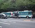 Dos Isuzu Erga Mio Autobuses en frente de Yasukuni Shrine con un Uyoku camión de ruido (Gaisensha) pasando por delante